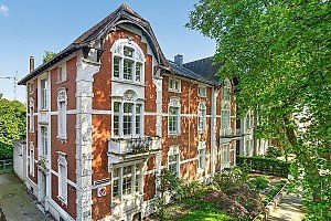 Foto Außergewöhnliches Wohn- und Geschäftshaus vereint historischen Charme mit vielseitigen Nutzungsmöglichkeiten. Die repräsentative Doppelhaushälfte wurde ursprünglich im Jahr 1902 in massiver Backsteinbauweise errichtet und prägt mit ihrer charaktervollen Architektur bis heute das Straßenbild.<br><br>